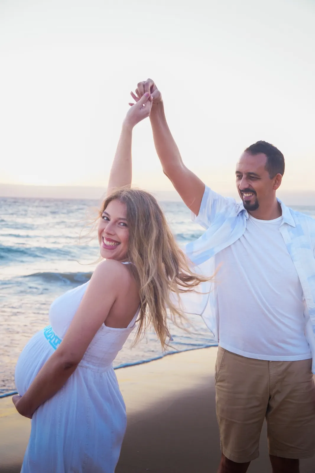 Casal a dançar na praia ao pôr do sol, numa sessão fotográfica